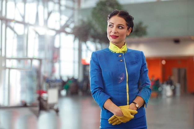 Asistente de vuelo femenino de pie en la terminal del aeropuerto