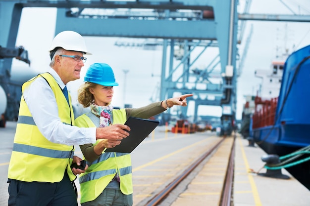 Asistiendo al jefe Dos trabajadores portuarios conversando entre ellos mientras inspeccionan el puerto