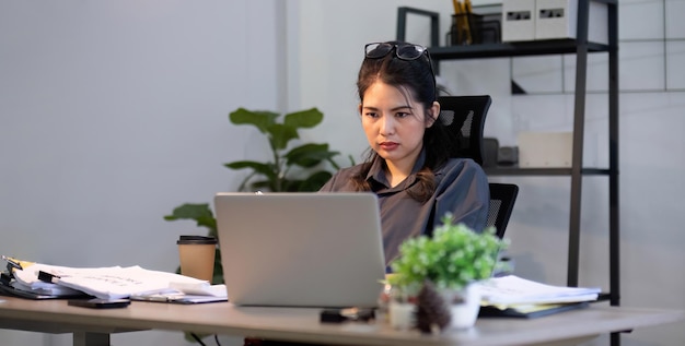 Asombrada confundida mujer asiática pensando duro preocupada por la solución de problemas en línea mirando la computadora portátil