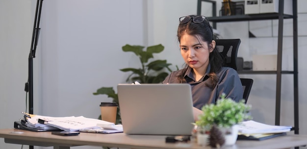 Asombrada confundida mujer asiática pensando duro preocupada por la solución de problemas en línea mirando la computadora portátil
