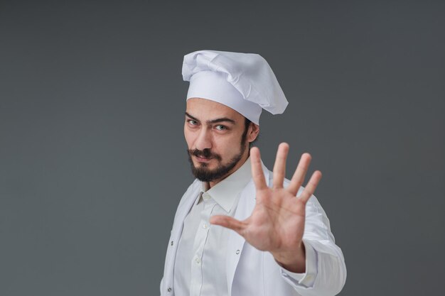 Asombrado joven chef italiano apuesto está gesticulando alerta y evita consejos en el cartel de la cocina cinco tomas de estudio incluye espacio de copia