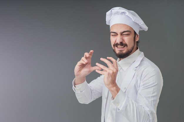 Asombrado joven chef italiano apuesto está gesticulando una deliciosa foto de estudio que incluye espacio de copia