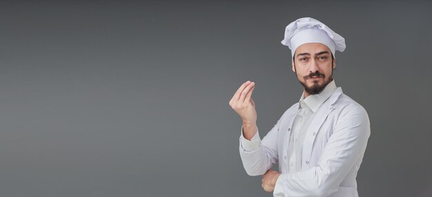 Asombrado joven chef italiano apuesto está gesticulando una deliciosa foto de estudio que incluye espacio de copia