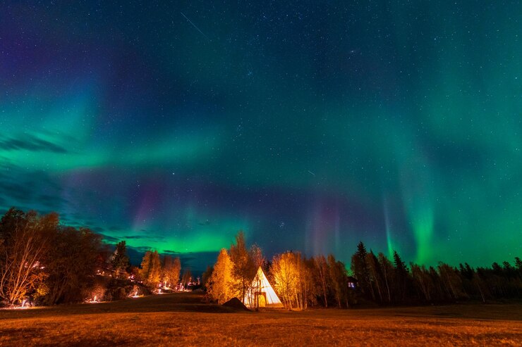 Asombrosas luces del norte bailando sobre las luces de Tipi o Tepees en la aldea Aurora en Yellowknife