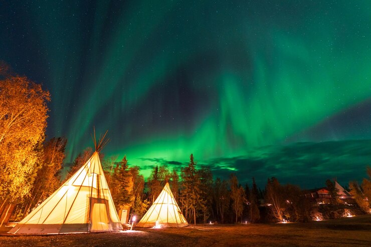 Asombrosas luces del norte bailando sobre las luces de Tipi o Tepees en la aldea Aurora en Yellowknife