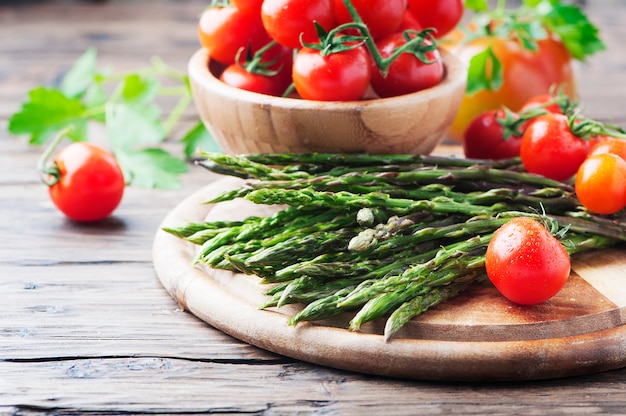 Aspargos crus com tomate na mesa de madeira