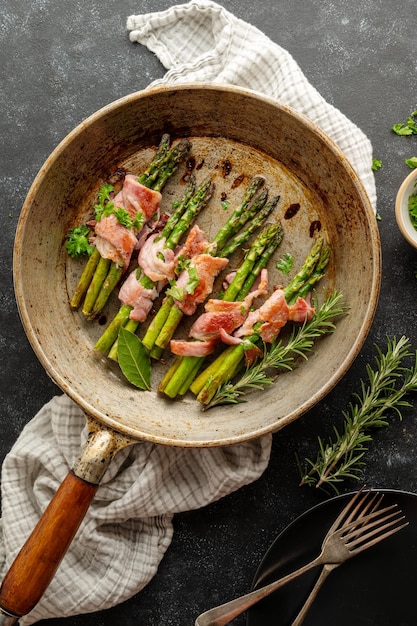 Aspargos embrulhados com bacon na frigideira Fundo escuro