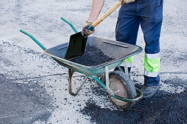 asphalt im schubkarrenbediener bereitet mischung mit uniform vor