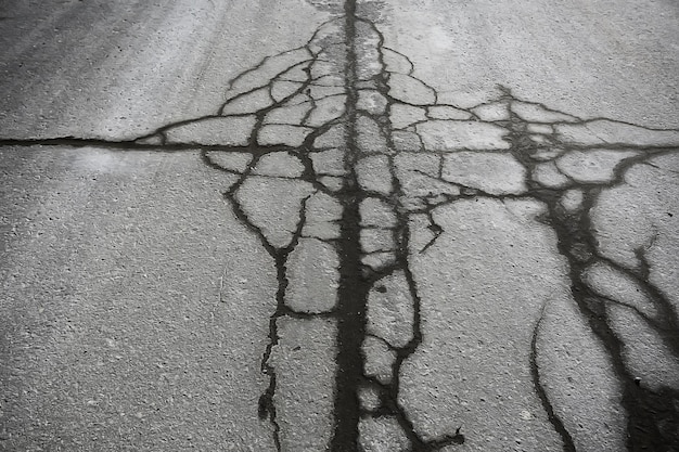 Foto asphalt in rissen textur / abstrakter hintergrund risse auf asphaltstraße