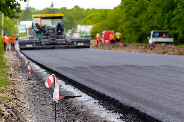 Asphaltfertiger auf der Straße während der Asphaltverlegung in Unschärfe. Straßenreparatur. Eine neue Straße bauen