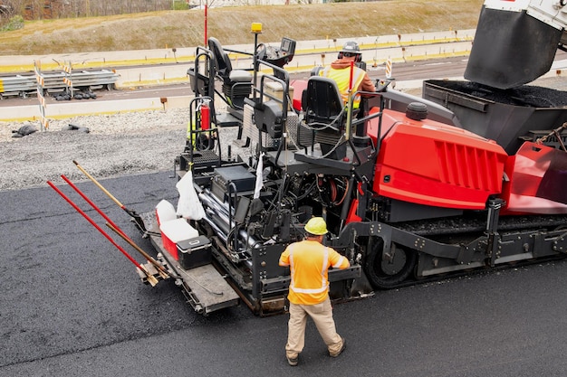 Asphaltfertigermaschine und Dampfstraßenwalze während des Straßenbaus und der Reparaturarbeiten