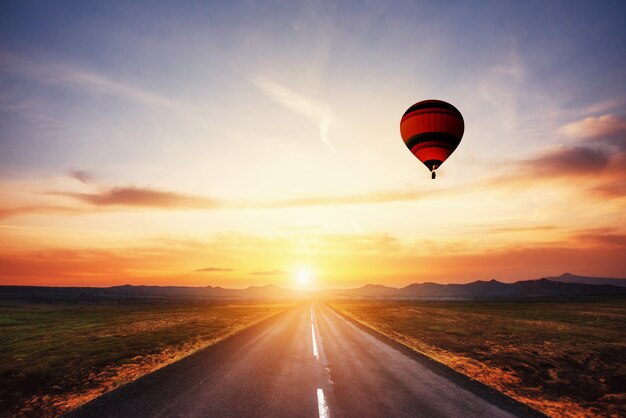 Asphaltstraße entlang und farbiger ball im himmel bei sonnenuntergang