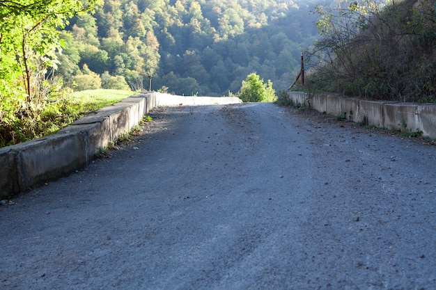 Asphaltstraße geht abends im Wald den Berghang hinunter