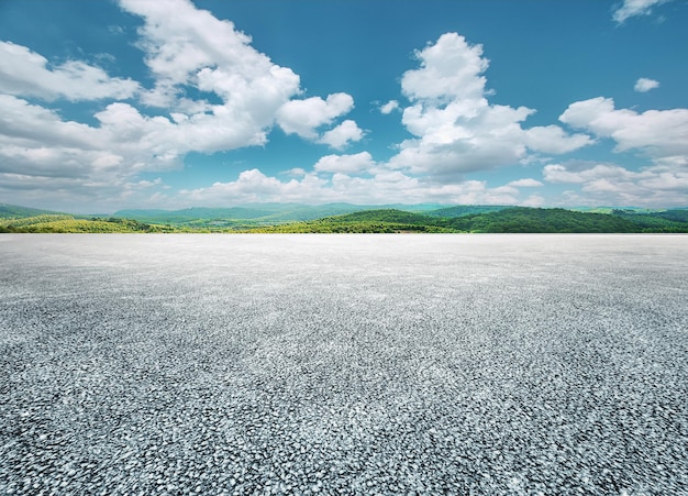 Asphaltstraße und grüne Bergnaturlandschaft unter blauem Himmel mit weißen Wolken