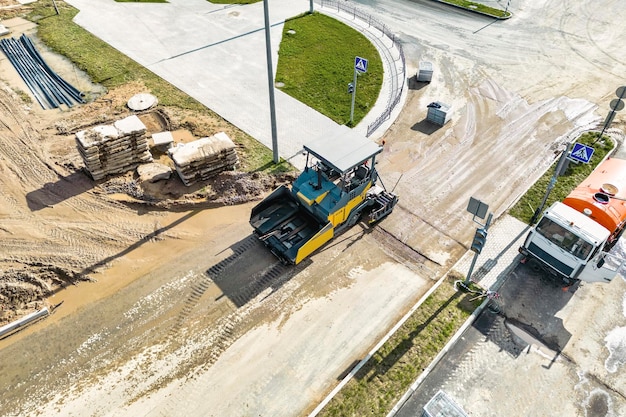 Asphaltverlegegeräte Asphaltfertigermaschine auf der Straßenreparaturstelle Straßenerneuerungsprozess Bauarbeiten Blick von oben Drohnenfotografie