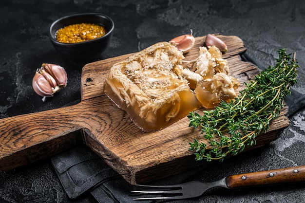 Aspic con carne de pollo sobre tabla de madera. Fondo negro. Vista superior.