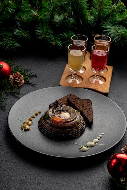 Aspik serviert mit Schwarzbrot auf einem dunklen Teller mit Senf und Meerrettich auf dunklem Weihnachtshintergrund