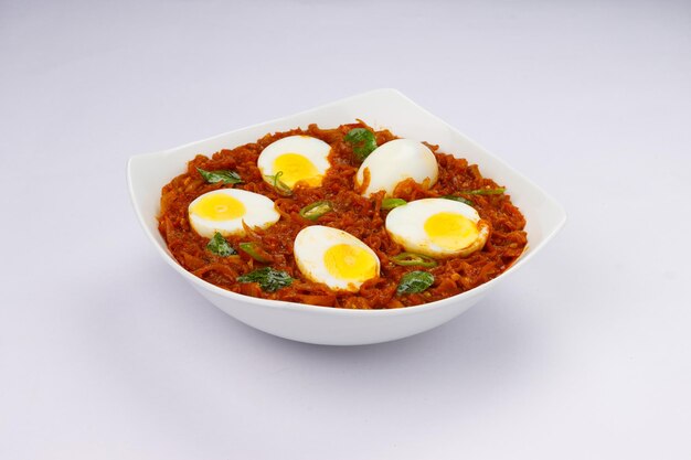 Assado de ovo ou ovo indiano masala curry assado de ovo vermelho picante disposto em uma tigela de cerâmica branca