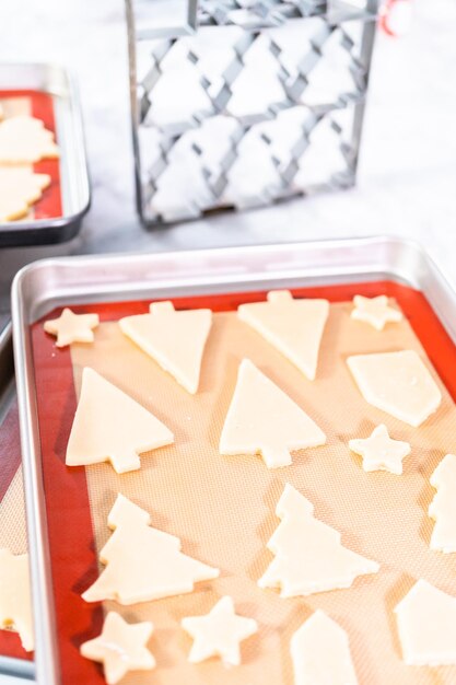 Assar biscoitos de Natal de açúcar em forma de árvores de Natal.