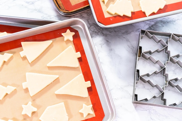 Assar biscoitos de Natal de açúcar em forma de árvores de Natal.