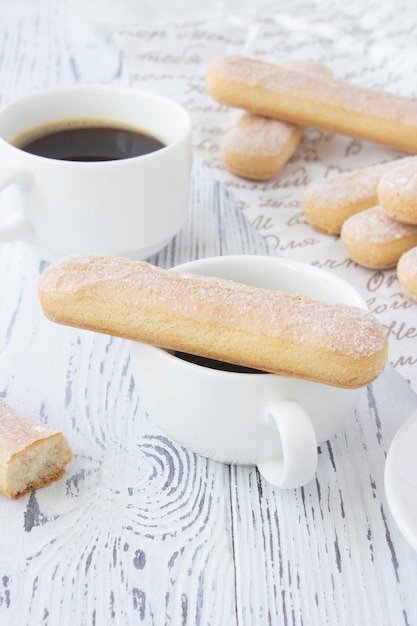 Assar biscoitos savoiardi biscoito para sobremesa tiramisu com café em um fundo branco de madeira