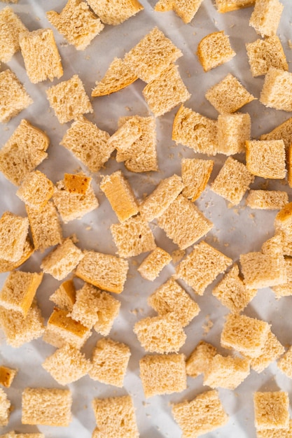 Assar croutons temperados com azeite e condimentados em uma assadeira forrada com papel manteiga