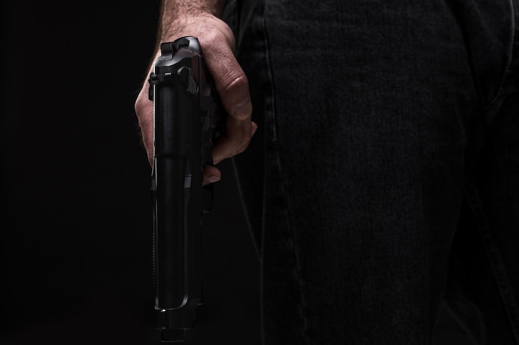 Foto assassino com arma em fundo preto no estúdio