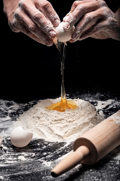 Asse. Perto do chef Melicio mãos preparando uma massa e usando ovos e farinha enquanto trabalhava em um restaurante.