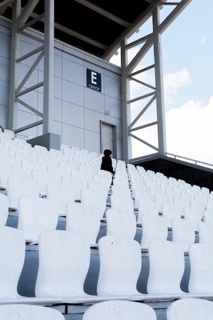 Assentos brancos na criança do estádio olha para longe