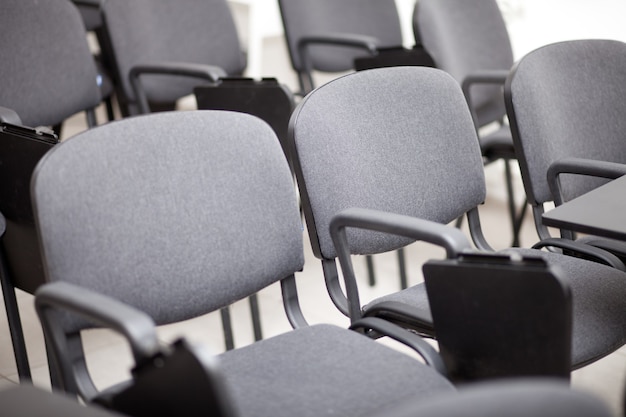 Assentos de cadeira cinza em uma sala de conferências vazia.