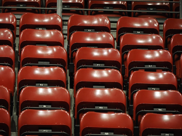 Assentos vermelhos brilhantes do estádio no estande