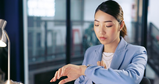 Assista o prazo e o computador com uma mulher asiática de negócios trabalhando tarde da noite em seu escritório para horas extras Contabilidade financeira e dedicação com uma funcionária trabalhando em seu local de trabalho corporativo