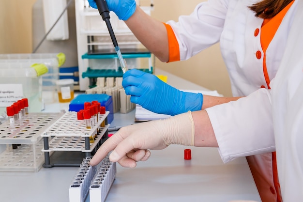 Assistência médica com conta-gotas. Tomando amostra de blod. Laboratório de diagnóstico. Foco seletivo nas mãos.