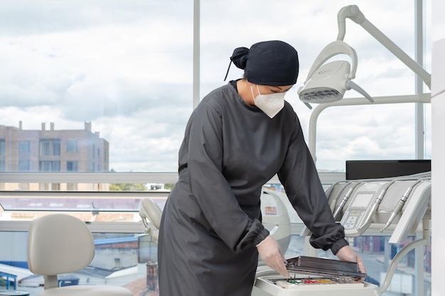 Assistente de dentista feminino preparando o equipamento clínico para atender a um paciente Conceito de clínica odontológica