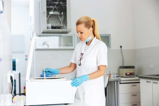 Assistente de laboratório colocando tubo de ensaio com amostra de sangue na máquina enquanto estava no laboratório.