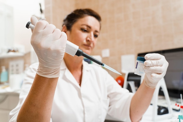 Assistente de laboratório com dispensador em laboratório fazendo análise de exames de sangue Equipamento médico em laboratório Cientista com dispensador de sangue fazendo análise hematológica de sangue