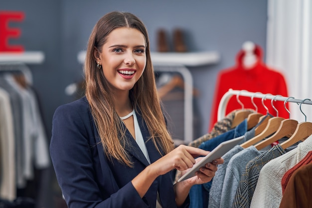 assistente de loja em sua boutique com a coleção outono-inverno