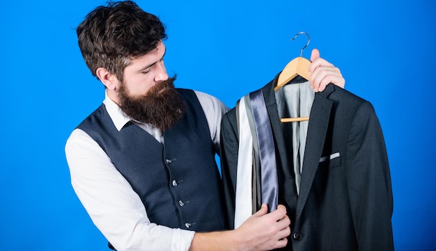 Assistente de loja ou serviço de estilista pessoal Gravata combinando com roupa Hipster barbudo homem segura gravatas e terno formal Cara escolhendo gravata Gravata perfeita Conceito de compras Conselho de estilista