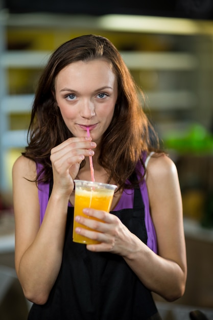 Assistente de loja tomando suco de frutas frescas