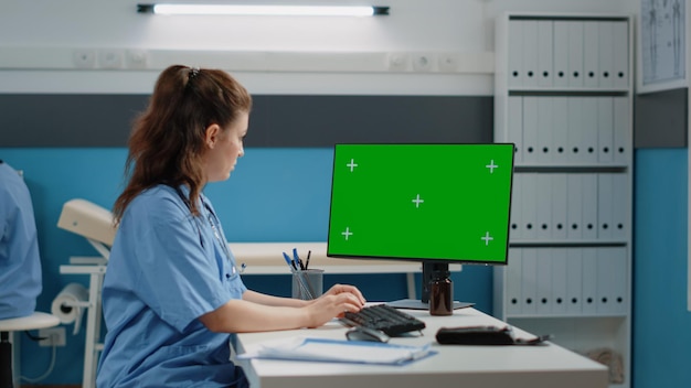 Assistente de saúde usando computador para tela verde horizontal