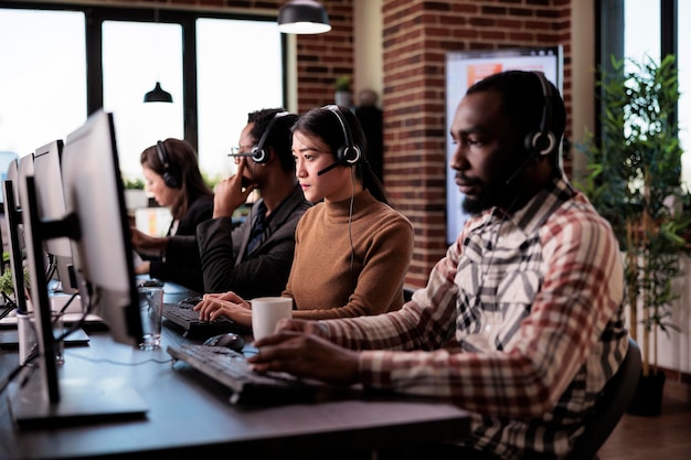 Assistente de vendas atendendo chamada de linha de apoio do cliente no helpdesk, trabalhando no centro de suporte ao cliente. Operador asiático dando assistência de telemarketing na rede de telefonia remota.