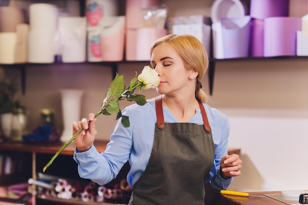 Assistente de vendas feminino trabalhando como florista e segurando o buquê com o cliente em segundo plano Forma horizontal da cintura para cima