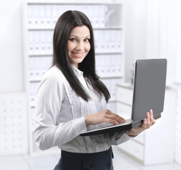 Assistente feminina usando laptop em pé no escritório