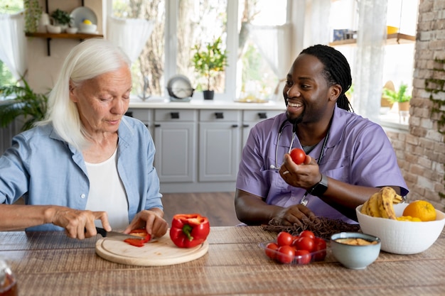 Assistente social fazendo comida com uma mulher idosa