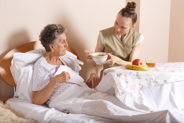 Assistente social sênior alimenta uma idosa de 80 anos