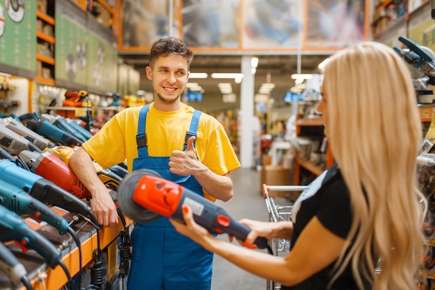 Assistentin und Einkäuferin im Baumarkt. Verkäufer in Uniform und Frau im Baumarkt, Einkaufen im Bausupermarkt