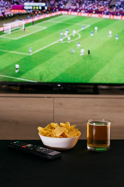 Foto assistindo o conceito de futebol com cerveja e batatas fritas