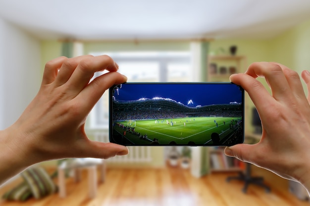 Assistir a um jogo de futebol em casa via smartphone. transmitindo futebol do estádio.