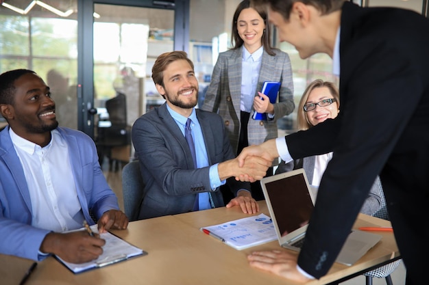 Foto associados de reunião de negócios apertando as mãos no escritório.