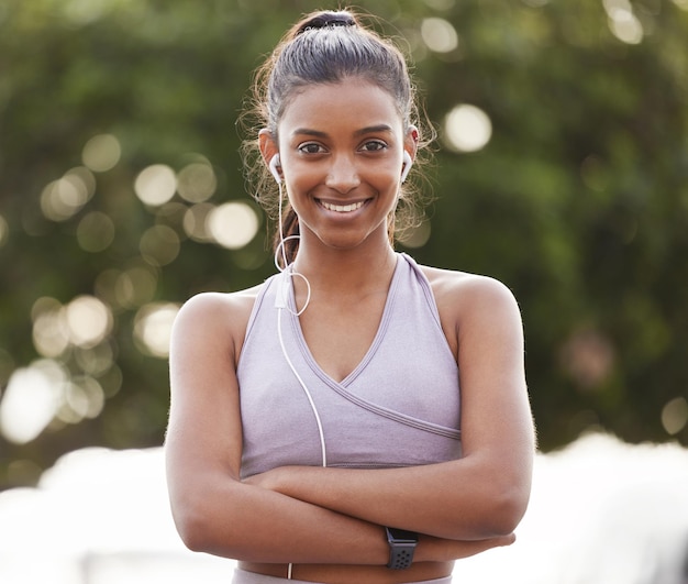 Foto assuma o controle de sua vida e veja uma mudança. retrato de uma jovem desportiva usando fones de ouvido e em pé com os braços cruzados durante o exercício ao ar livre.